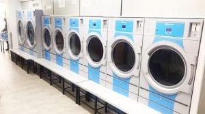 Row of commercial laundry equipment in a laundry room