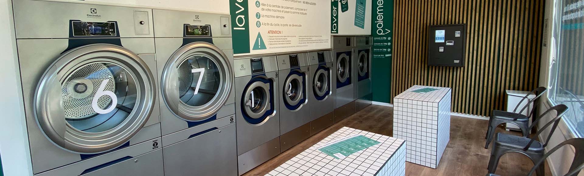 Modern laundromat interior with a row of Electrolux washing machines and a comfortable seating area