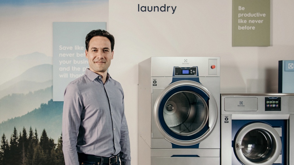 Man standing beside Commercial Washer and Dryer Man standing beside Commercial Washer and Dryer