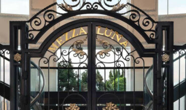 A majestic black gate with white flowers and black stairs on both sides