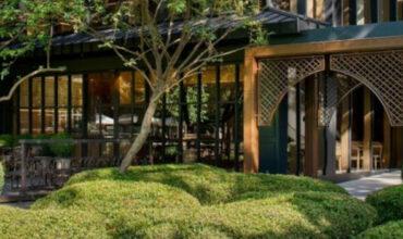 Modern exterior of École Ducasse Nai Lert Bangkok Studio surrounded by trees and gardens