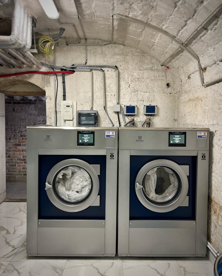 Electrolux Professional washing machines in hotel laundry room with stone walls