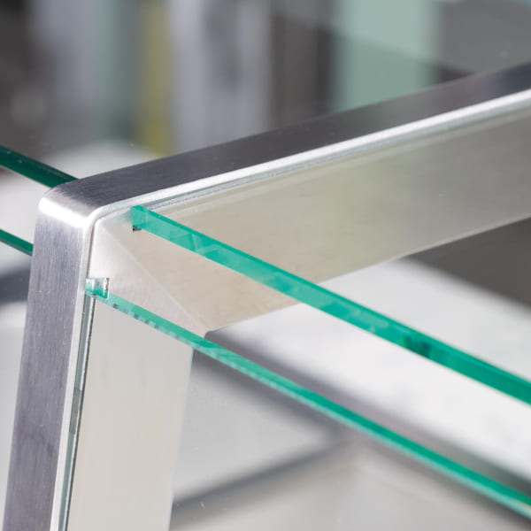 Close-up of a modern glass and stainless steel structure featuring precision-cut glass panels secured within a sleek metal frame, emphasizing contemporary design and craftsmanship.