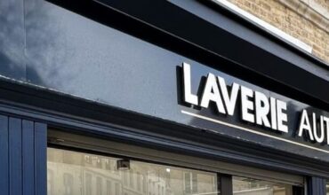 A blue storefront featuring a sign that reads "laverie automatique" showcasing a vibrant and inviting exterior.