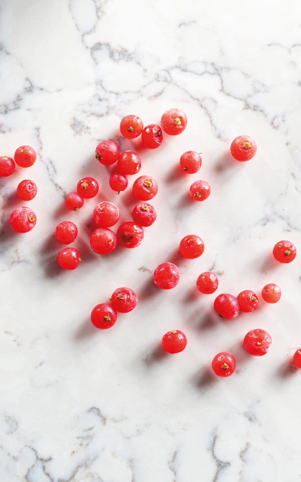 Fresh red currants scattered on a marble surface.