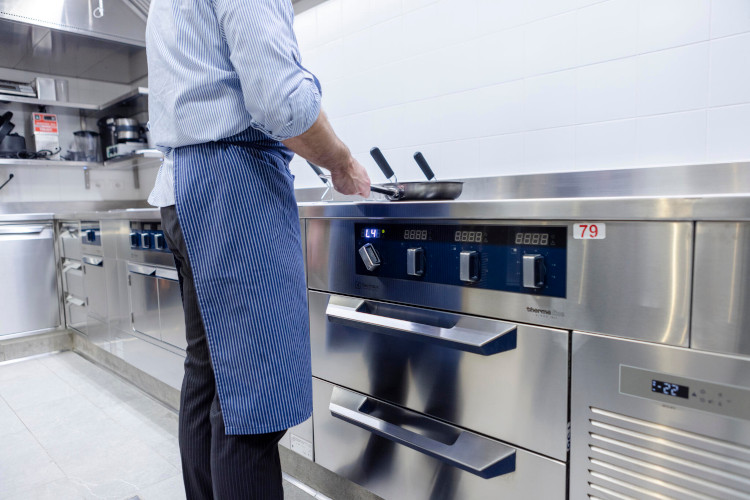 onde_thermaline Professional cooking station with working chef, equipped with stainless steel equipment