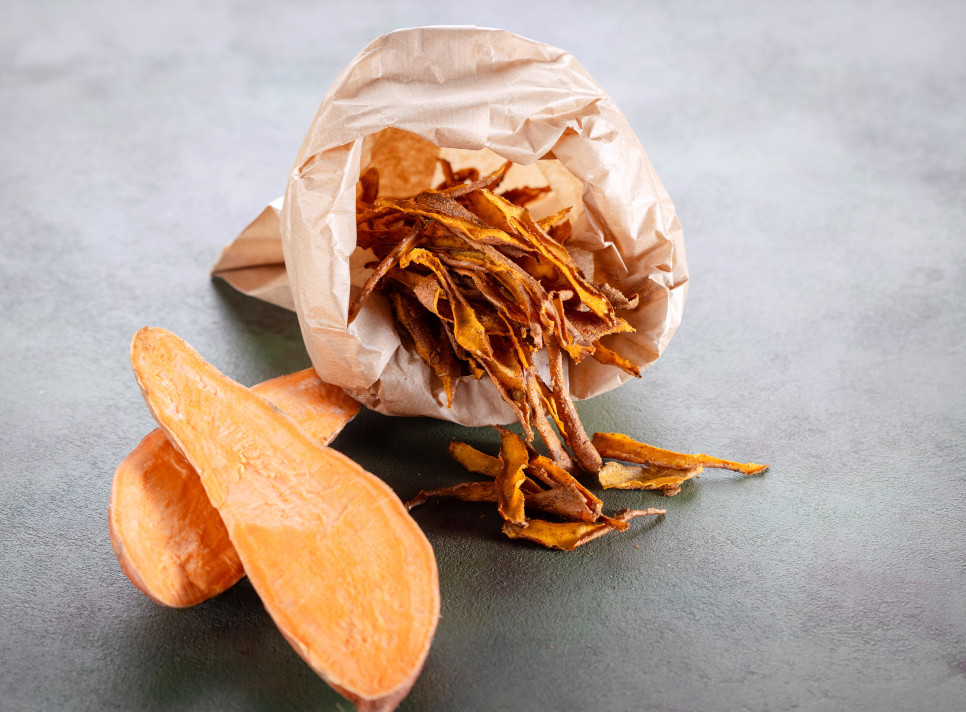 Zero waste sweet potato peel chips in a paper bag with raw sweet potatoes on the side